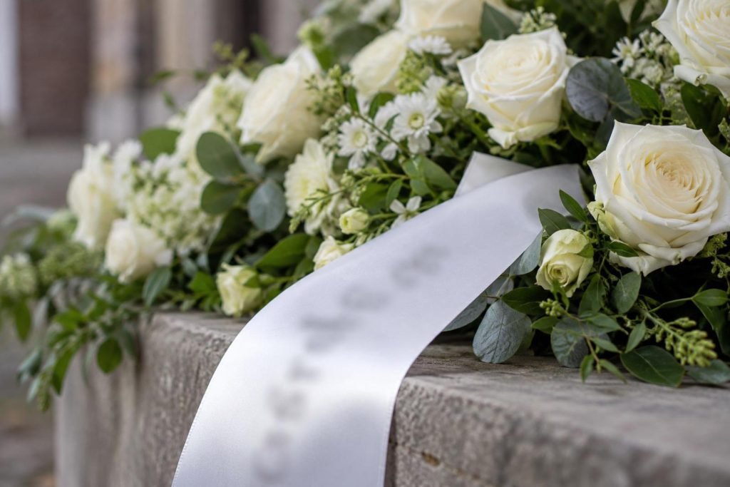 Wit lint over de rand van een rouwstuk met witte rozen